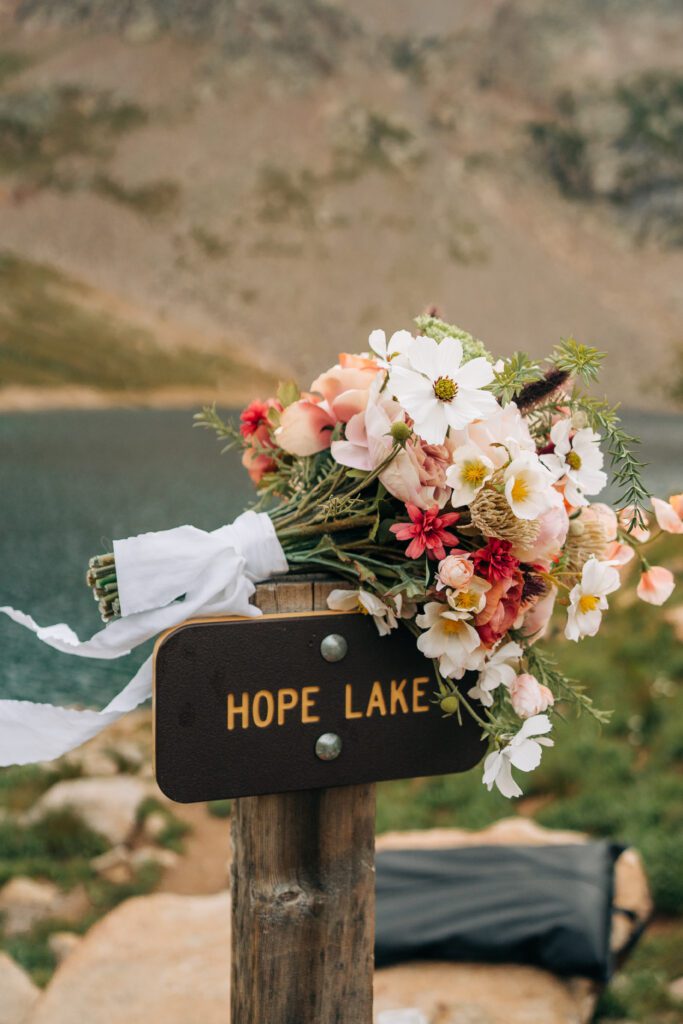 Brides bouquet sitting on top of the Hope Lake sign during their Telluride Elopement