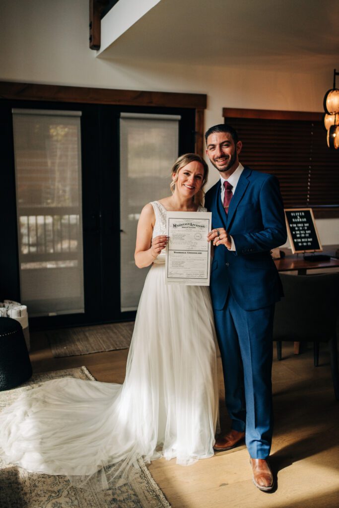 Bride and groom holding their marriage license and smiling at the camera after their rocky mountain national park elopement