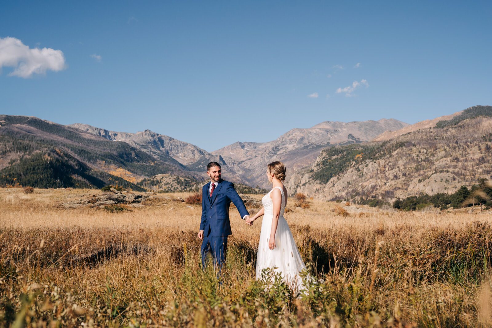 Bride and groom holding hands and walking through the meadows at Moraine Park during their Rocky Mountain National Park elopement