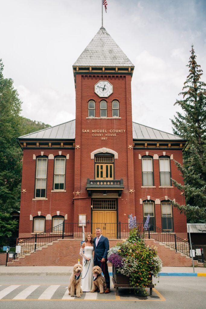 Bride and groom standing in front of the Telluride courthouse with their dogs during their Telluride elopement