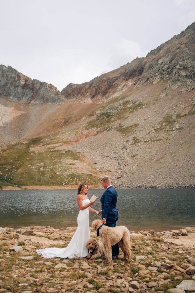 Bride reading her marriage vows to the groom at an alpine lake during their Telluride elopement ceremony