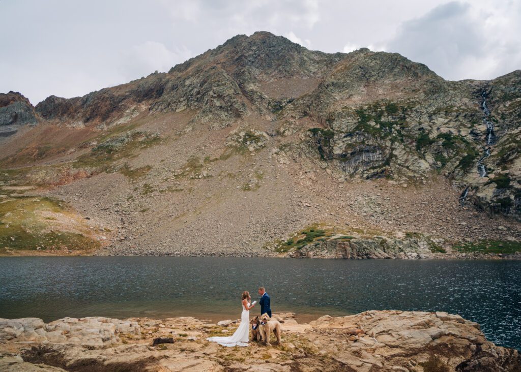 bride reading her vows to groom in front of an alpine lake during their Telluride elopement