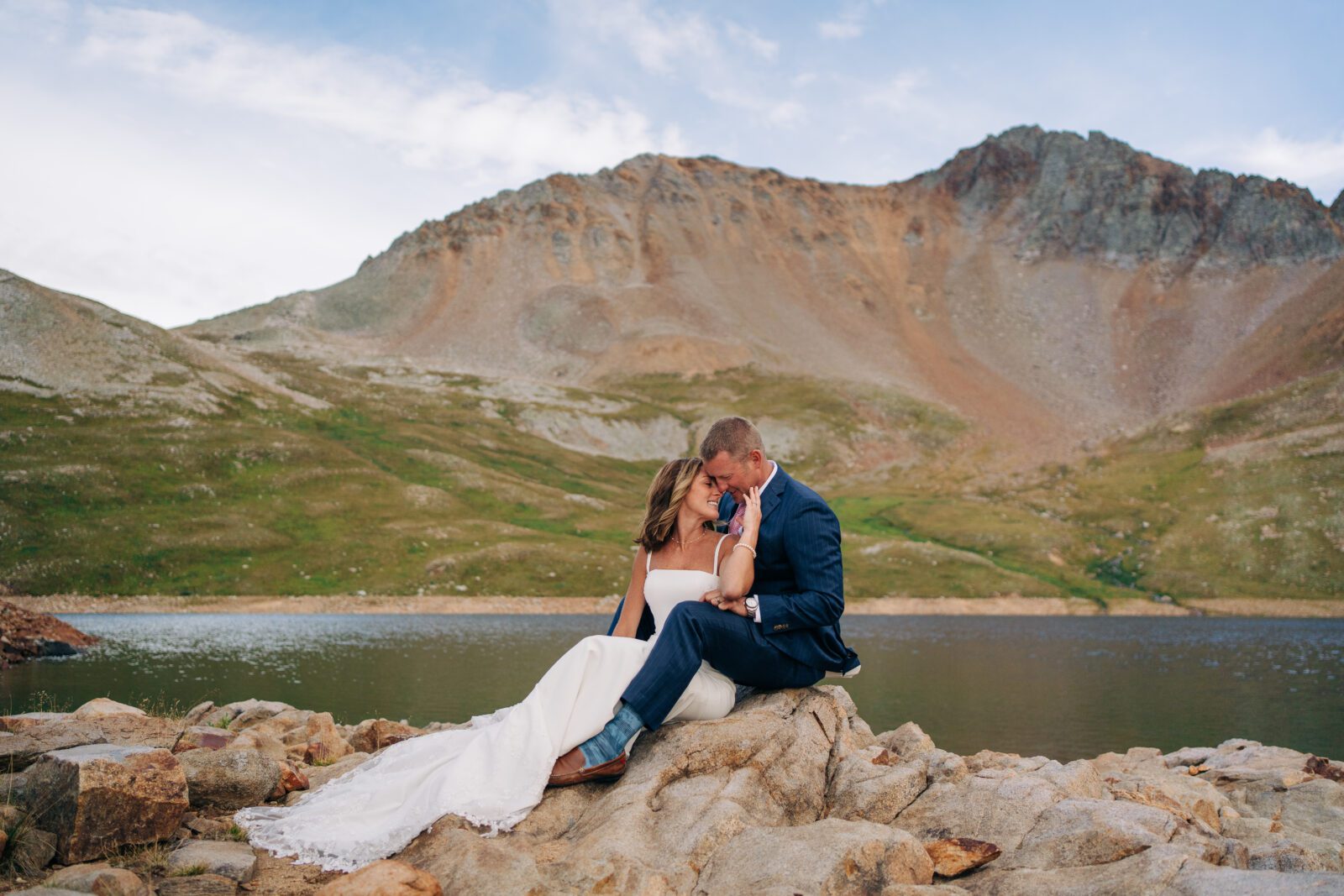 Bride sitting between grooms legs on a rock at Hope lake during their Telluride elopement