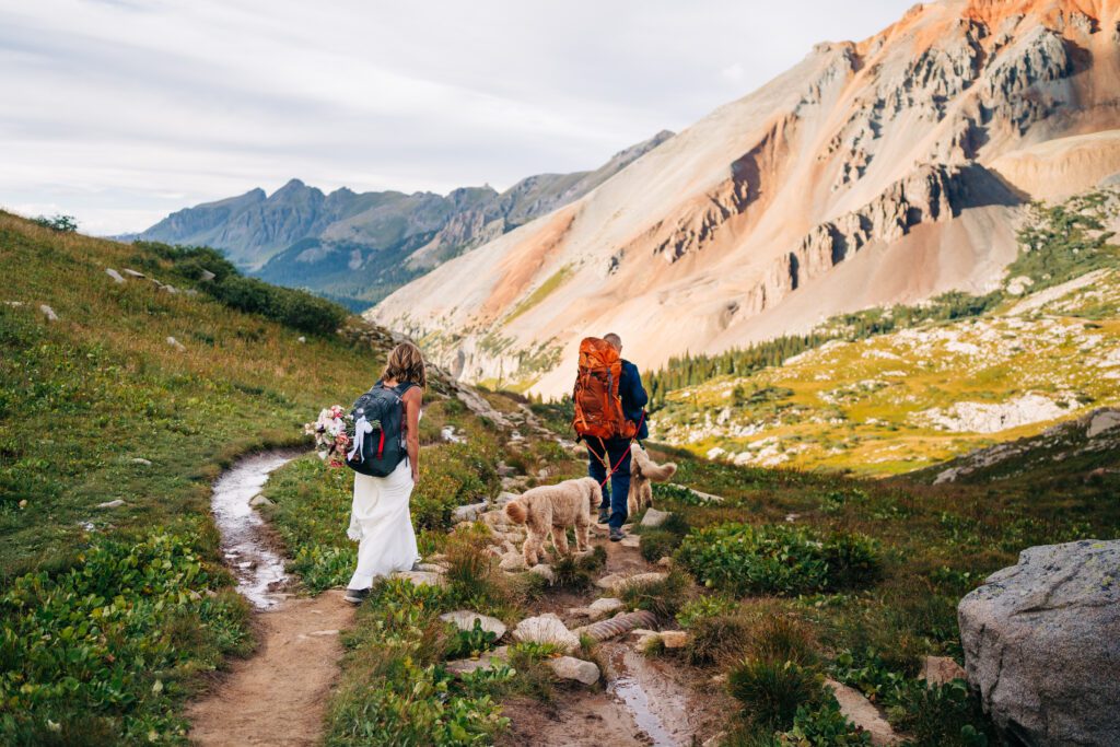 Bride and groom with their hiking gear on as they traverse a hiking trail in the San Juan mountains during their Telluride elopement