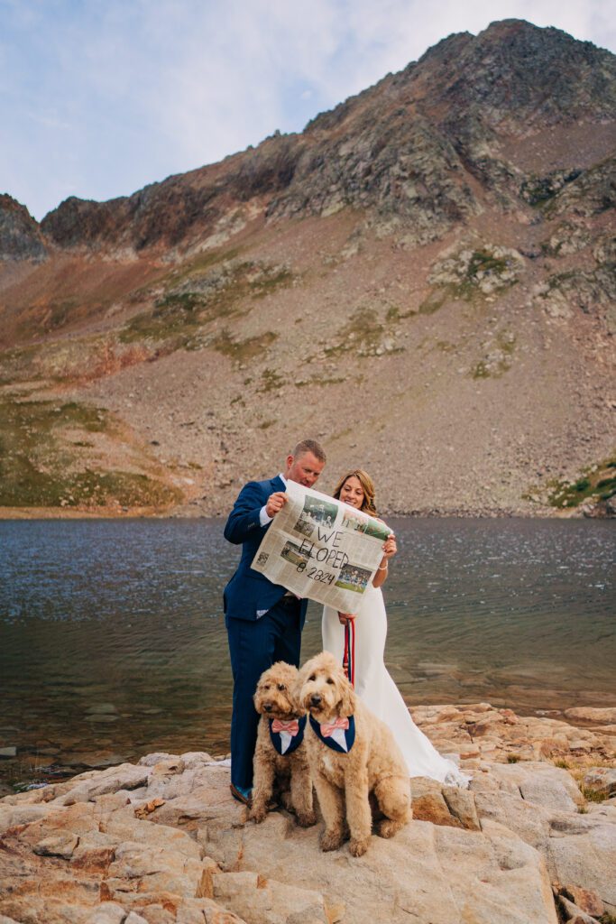 bride and groom holding a newspaper that says "we eloped" on it during their Telluride elopement at Hope Lake