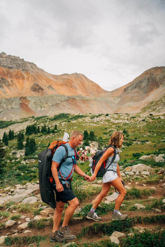 Bride holding her grooms hand leading him up a hiking trail in the San Juan Mountains at Hope Lake during their Telluride elopement