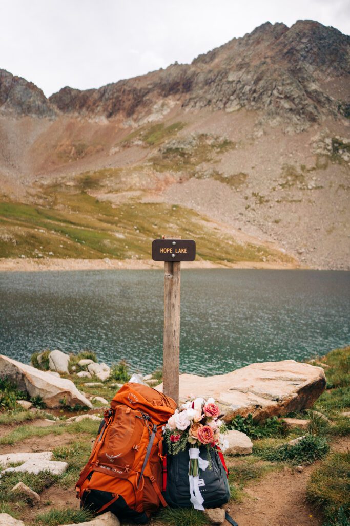 Bride and grooms backpack sitting next to Hope Lakes sign during their Telluride elopement