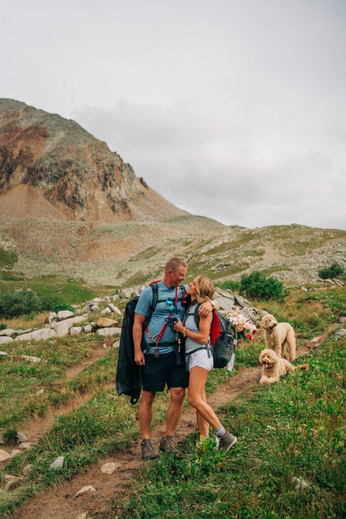 Bride smiling up at groom as he hugs her during their Telluride elopement hike at Hope Lake located in the San Juan Mountains